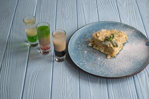 das Cocktails und Napoleon Kuchen auf ein Blau hölzern Tisch. foto