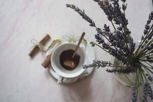 ein Tasse von Kaffee mit Zimt und Lavendel Blume auf ein Tisch. foto