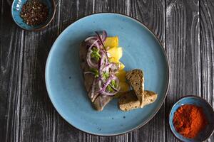 gebraten Kartoffeln und Hering Fisch mit Zwiebel auf ein hölzern Tisch. foto