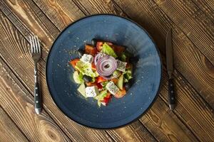 griechisch Salat im ein Teller auf ein hölzern Tisch. foto