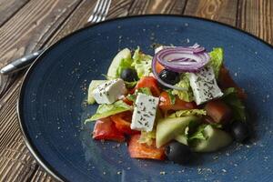 griechisch Salat im ein Teller auf ein hölzern Tisch. foto