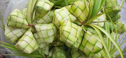 Ketupat oder Reis Knödel. ein traditionell Reis Gehäuse gemacht von jung Kokosnuss Blätter zum Kochen Reis verkauft im traditionell Markt Vorbereitung zum das eid al-fitr Urlaub zum Muslim foto
