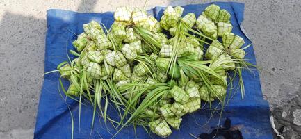 Ketupat oder Reis Knödel. ein traditionell Reis Gehäuse gemacht von jung Kokosnuss Blätter zum Kochen Reis verkauft im traditionell Markt Vorbereitung zum das eid al-fitr Urlaub zum Muslim foto