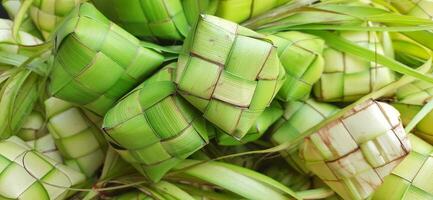 Ketupat oder Reis Knödel. ein traditionell Reis Gehäuse gemacht von jung Kokosnuss Blätter zum Kochen Reis verkauft im traditionell Markt Vorbereitung zum das eid al-fitr Urlaub zum Muslim foto