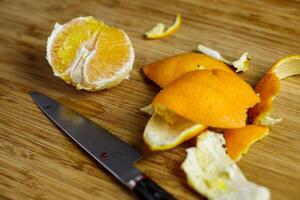 Orange geschält und Schnitt auf hölzern Schneiden Tafel mit schälen und japanisch Messer foto