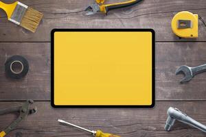Tablette Attrappe, Lehrmodell, Simulation zum App Förderung, umgeben durch Werkzeuge auf hölzern Tisch. perfekt zum präsentieren Ihre App. oben Sicht, eben legen Komposition. DIY Konzept foto