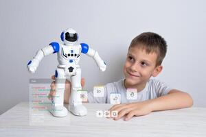 Junge ist halten ein Roboter im seine Hand mit konzeptionelle Roboter Programmierung Code foto