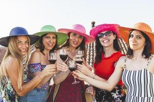 Gruppe von weiblich freunde tragen Hüte Toasten rot Wein foto