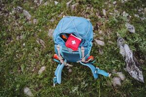 Tourist Ausrüstung stellen ein Erste Hilfe Kit im ein Rucksack, ein rot zuerst Hilfe Kit ist im das Tasche von das Tasche, Ausrüstung zum Wandern im das Berge, Trekking allein. foto