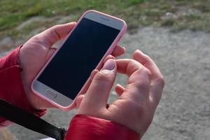 Eine Frau hält ein Handy in zwei Händen. dunkler Bildschirm in einem Smartphone. foto