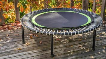 Mini Trampolin zum Fitness ausüben und abprallen im ein Hinterhof Terrasse, fallen Landschaft foto