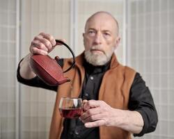 Senior Mann Gießen Tee in Glas foto