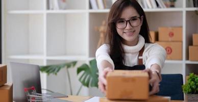 Porträt einer asiatischen jungen Frau, die zu Hause mit einer Kiste am Arbeitsplatz arbeitet. Start-up-Kleinunternehmer, Kleinunternehmer-KMU oder freiberufliches Online- und Lieferkonzept. foto