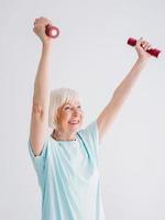 Senior fröhliche Frau, die Sport mit Hanteln macht. Anti-Age, Sport, gesundes Lebensstilkonzept foto