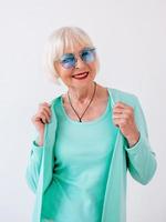 Senior stilvolle fröhliche Frau in blauer Sonnenbrille und türkisfarbener Kleidung. Sommer, Reisen, Anti-Age, Freude, Ruhestand, Freiheitskonzept foto