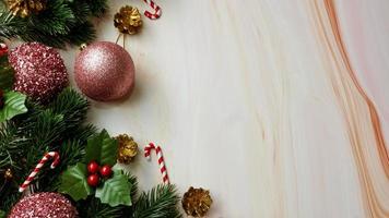 grüne Kiefernblätter, rosa Weihnachtsdekorationen und Zuckerstangen auf weichem Marmorhintergrund, Weihnachtsdekorationen in heller und ausgefallener rosa Farbe. einfaches und kreatives Weihnachtskonzept. foto