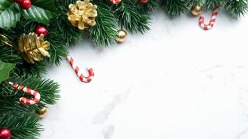 grüne Kiefernblätter, rote Weihnachtsdekorationen und Zuckerstangen auf weißem Marmorhintergrund, Weihnachtsdekorationen in leuchtend roter Farbe. einfaches und kreatives Weihnachtskonzept.