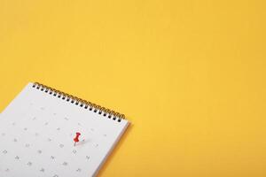 Markieren Sie den Veranstaltungstag mit einer Stecknadel. Reißnägel im Kalenderkonzept für geschäftige Zeitleiste, Zeitplan, Terminerinnerung. planung von geschäftstreffen oder reiseplanungskonzept. Weicher Fokus foto