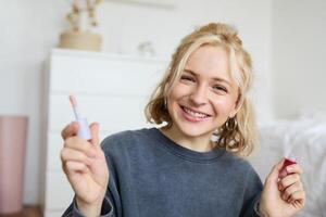 schließen oben Porträt von Frau Aufzeichnung ein von Sie selber, halten Schönheit Produkt, empfehlen Lippe Glanz, Inhalt Hersteller Werbung bilden auf ihr Blog, lächelnd beim Kamera foto