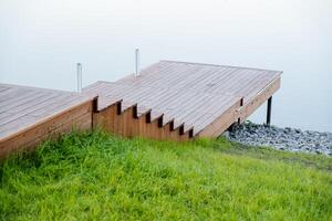 ein hölzern Seebrücke auf das See, ein Promenade zu ein Teich, ein Fluss Damm, ein Stadt Erholung Park, Parkplatz zum Boote, ein Stein Bank, ein ruhig Ort, ein Brücke zu das Fluss. foto