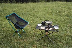 Camping Möbel, falten Stuhl und Tisch, draussen Erholung, Vorbereitung von ein Lager Küche, Frühstück im das Berge, Tourist Teller, Ausrüstung zum Trekking. foto