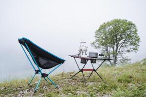 Camping im das Wald, Morgen Nebel, Wandern Möbel, Camping Gang, draussen Erholung Ausrüstung, Geschirr auf das Tisch. foto
