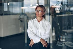 konzentriert Geschäft Frau tragen Brille sieht aus Weg während das Arbeiten Tag beim modern Büro foto