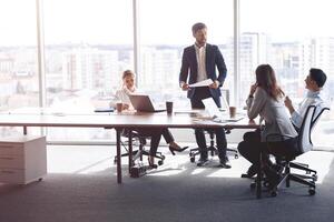 Menschen Stehen in der Nähe von Tisch, Mannschaft von jung Geschäftsleute Arbeiten und kommunizieren zusammen im Büro foto