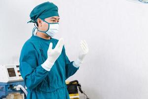 Arzt mit Handschuhen, der sich vor der Operation im Operationssaal vorbereitet foto