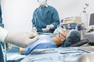 Assistent gibt Chirurgen während der Operation Instrumente aus. OP- und Notfallkonzept foto