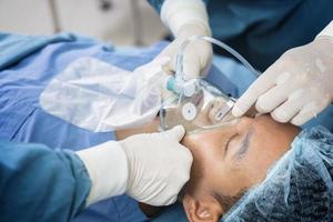 Der Assistenzarzt legt dem Patienten zur Vorbereitung der Operation eine Beatmungs-Sauerstoff-Maske an. foto