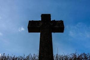 großes dunkles religiöses Kreuz gegen einen blauen sonnigen Himmel