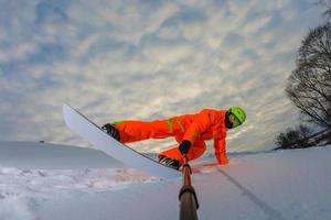 Snowboarder macht einen Trick und macht ein Selfie foto