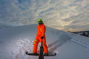 Snowboarder mit dem Snowboard macht ein Selfie foto