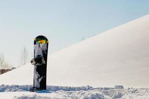 Snowboard- und Skibrille, die auf einem Schnee in der Nähe der Freeride-Piste liegt foto