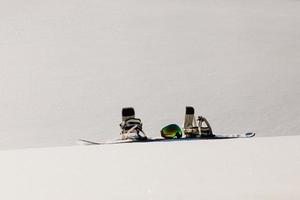 Snowboard- und Skibrille, die auf einem Schnee in der Nähe der Freeride-Piste liegt foto