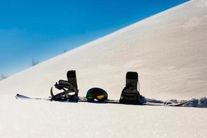 Snowboard- und Skibrille, die auf einem Schnee in der Nähe der Freeride-Piste liegt foto