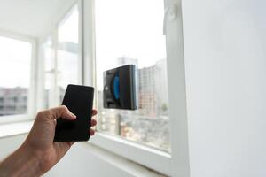 modern Fenster Unterlegscheibe Roboter führt aus Arbeit auf ein schmutzig Fenster. Reinigung das Haus mit Clever Geräte. automatisch Fenster Reinigung Roboter, Haushälterin foto