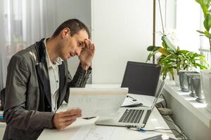 Geschäft, Menschen, scheitern, Papierkram und Technologie Konzept - - Geschäftsmann mit Laptop Computer und Papiere Arbeiten im Büro foto