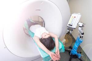 hübsch, jung Frau gehen durch ein computerisiert axial Tomographie Katze Scan medizinisch Prüfung Untersuchung im ein modern Krankenhaus foto