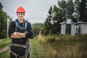 junger Mann, der mit Telekommunikationshintergrund steht foto