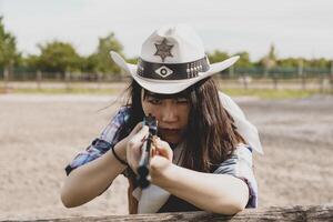 Porträt von ein schön Chinesisch weiblich Cowgirl Schießen mit ein Waffe foto