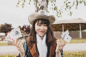 Porträt von ein schön Chinesisch weiblich Cowgirl spielen mit Poker Karten foto