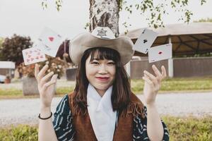 Porträt von ein schön Chinesisch weiblich Cowgirl spielen mit Poker Karten foto