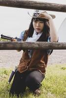 Porträt von ein schön Chinesisch weiblich Cowgirl Schießen mit ein Waffe foto