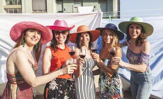 Gruppe von weiblich freunde tragen Hüte Toasten rot Wein foto