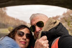 glücklich Mitte alt Paar auf Ferien nehmen ein Selfie auf das Banken von das Tiber im Rom foto