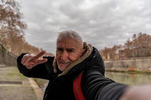 glücklich Mitte alt Mann auf Ferien nehmen ein Selfie auf das Banken von das Tiber Fluss im Rom foto