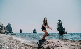 Frau Sommer- Reise Meer. glücklich Tourist im Hut genießen nehmen Bild draußen zum Erinnerungen. Frau Reisender posieren auf das Strand beim Meer umgeben durch vulkanisch Berge, Teilen Reise Abenteuer Reise foto