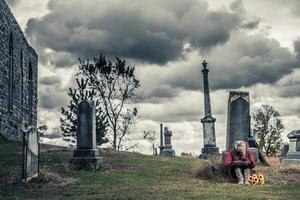 einsame traurige junge Frau in Trauer vor einem Grabstein